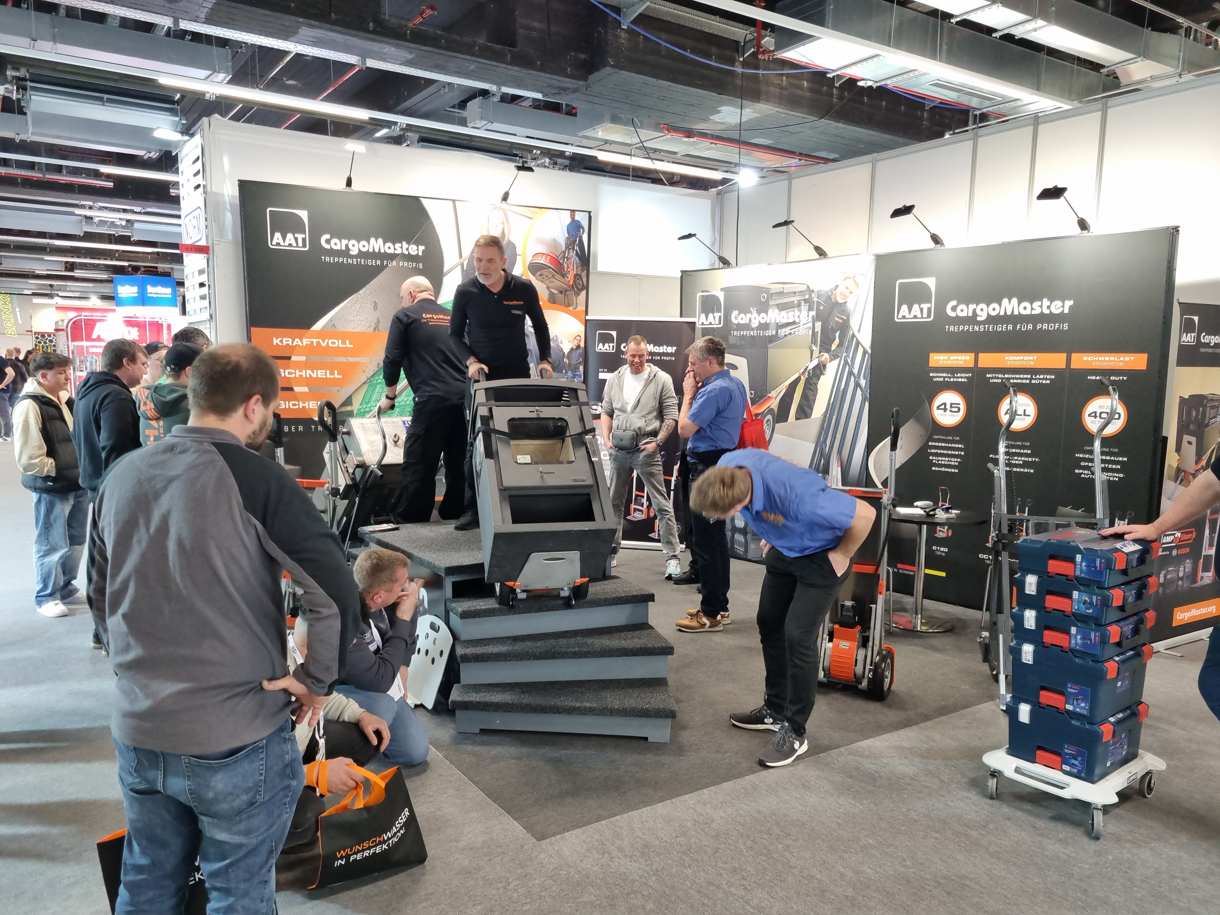 The image shows one of our employees at our booth, presenting our CargoMaster devices to interested visitors.