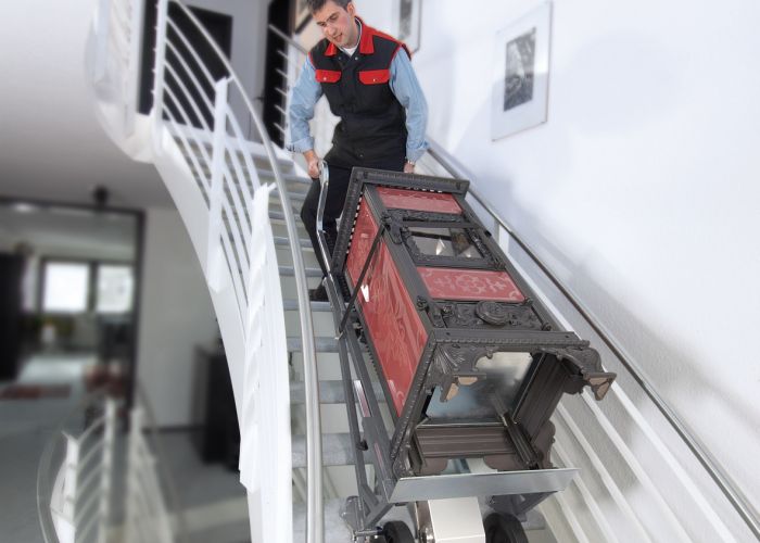 Das Bild zeigt den Einsatz des CargoMaster Treppensteigers A350 beim Transport eines Ofens über Treppen.